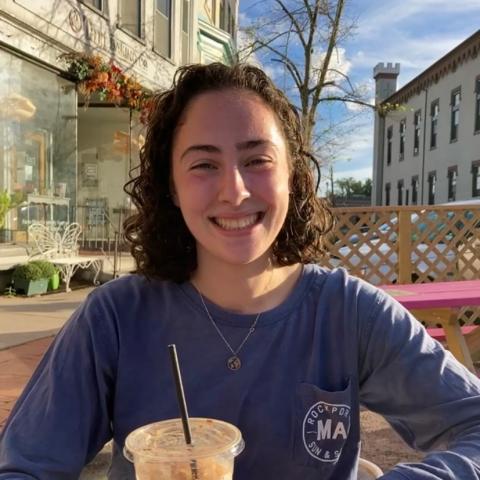 Photo of Lilly drinking coffee outside.