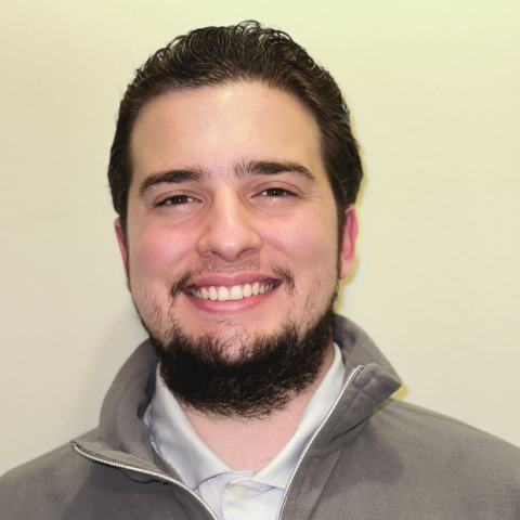 James is smiling in front of a neutral background.