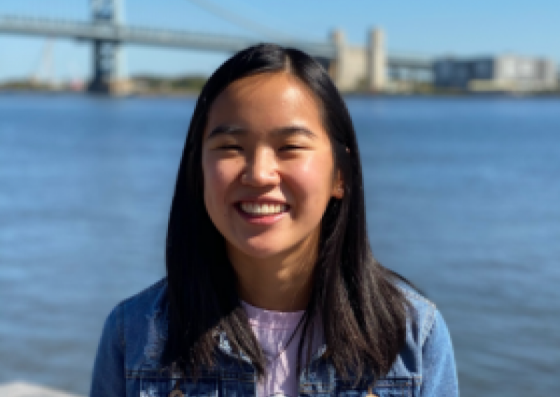 NHC PGH member Lily smiling on a sunny day with a bridge in the background