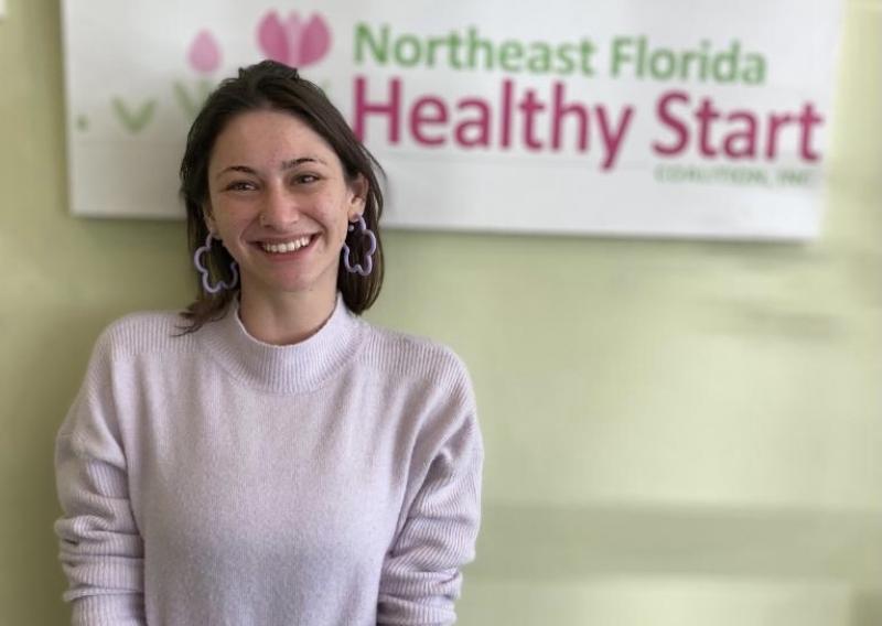 Philine standing in front of host site sign