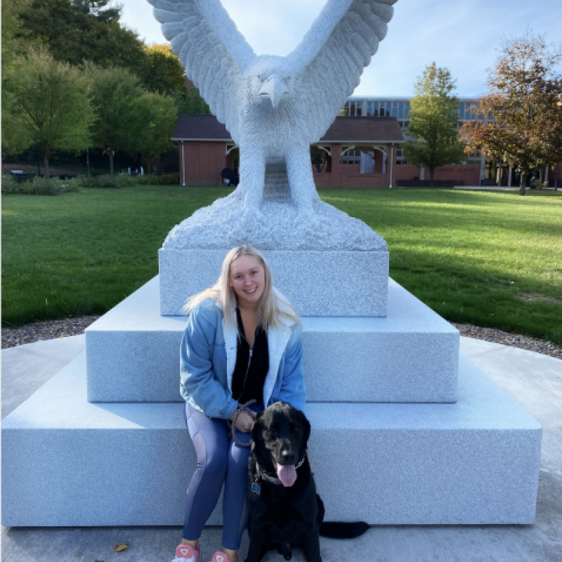 NHC PGH member Laurel smiling in front of a statue with her dog