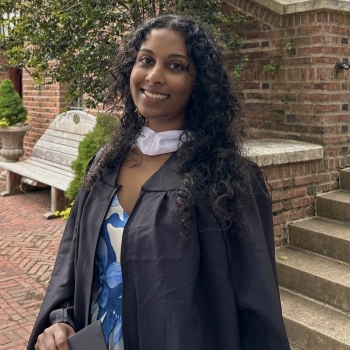 Maya standing in a courtyard in a graduation gown