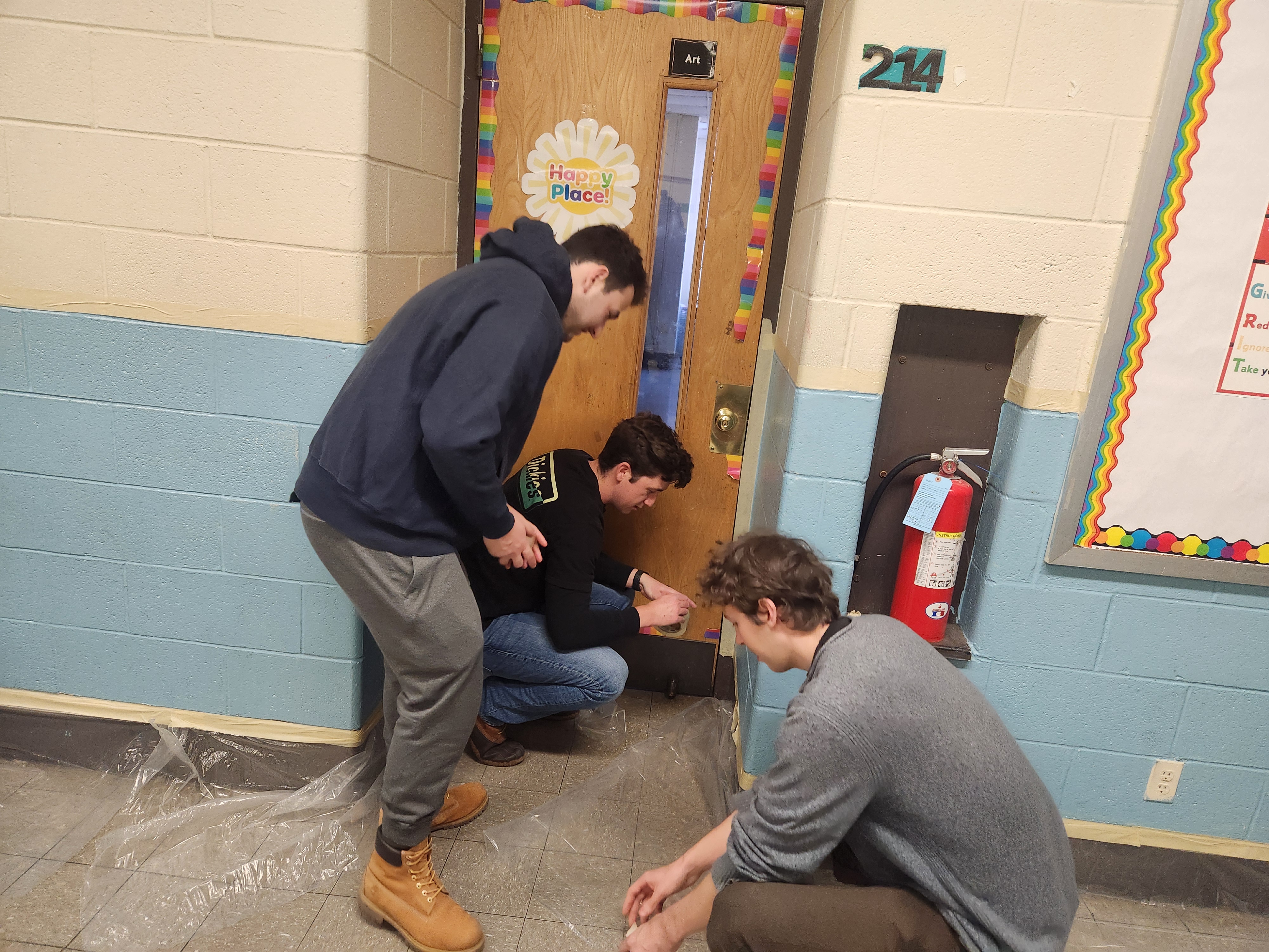 "Three Americorps members preparing to paint wall of a school during a service project"