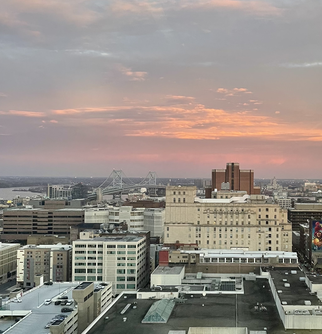 A sunset with buildings and the Ben Franklin Bridge in the foreground